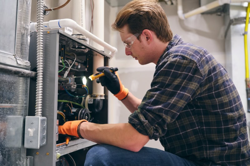 5 Reasons to Schedule a Fall Furnace Clean and Check. Tech in fron of furnace.
