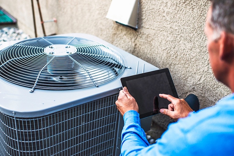 Maintenance engineer using digital tablet to inspect air conditioning unit