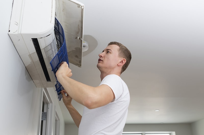 Young man cleaning filters in the air-conditioning split device